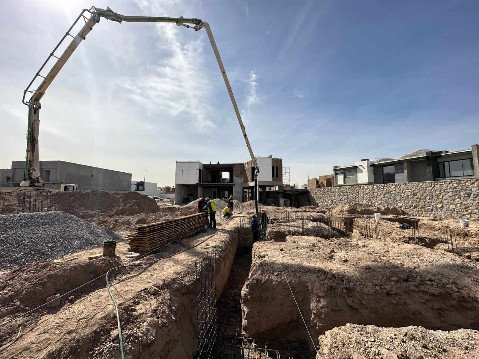 Bomba de concreto vertiendo mezcla sobre zapatas corridas y cimentación en terreno de obra residencial